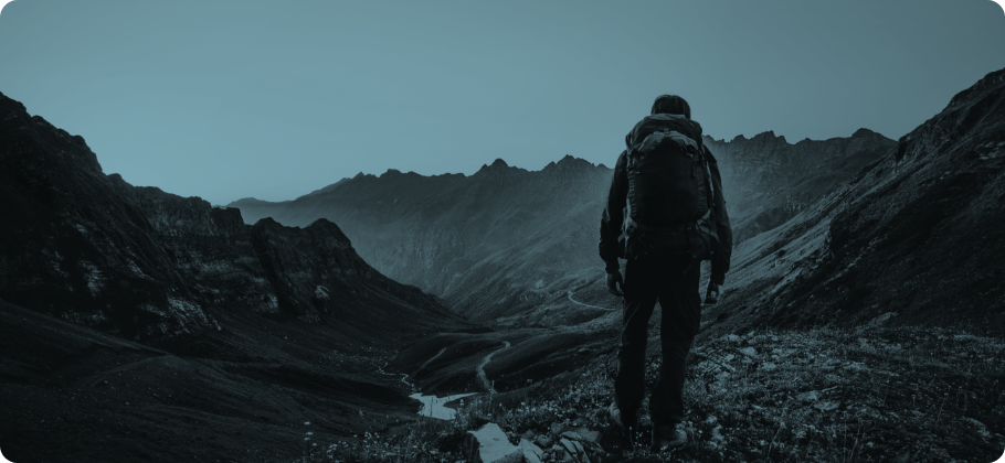 A man with a backpack hiking on a mountain trail.