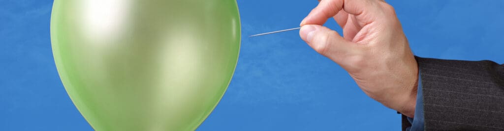 Man’s hand about to pop a balloon with a pin