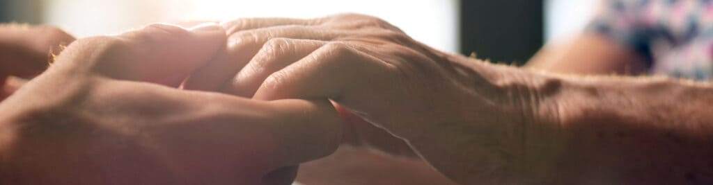 Young person holding an old person’s hands for support